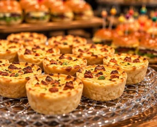 Mini quiches dourados servidos em travessa de cristal